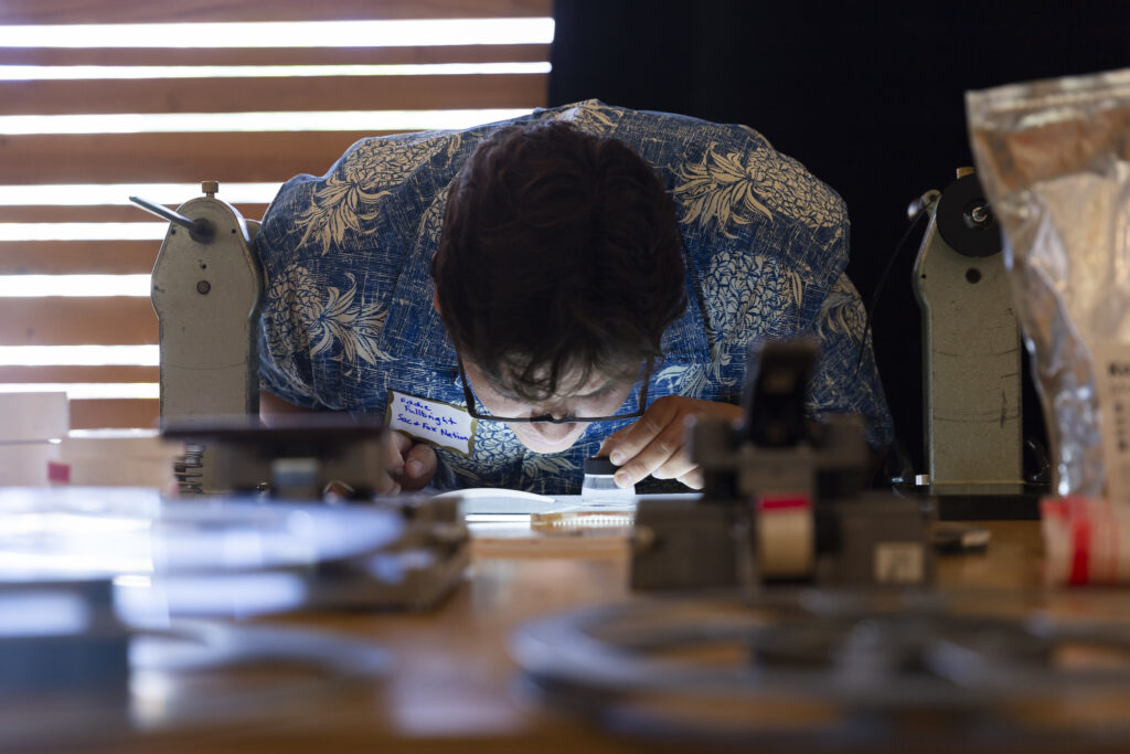 Workshop participant inspects a film through a loop and light box during the Community Archiving Workshop.